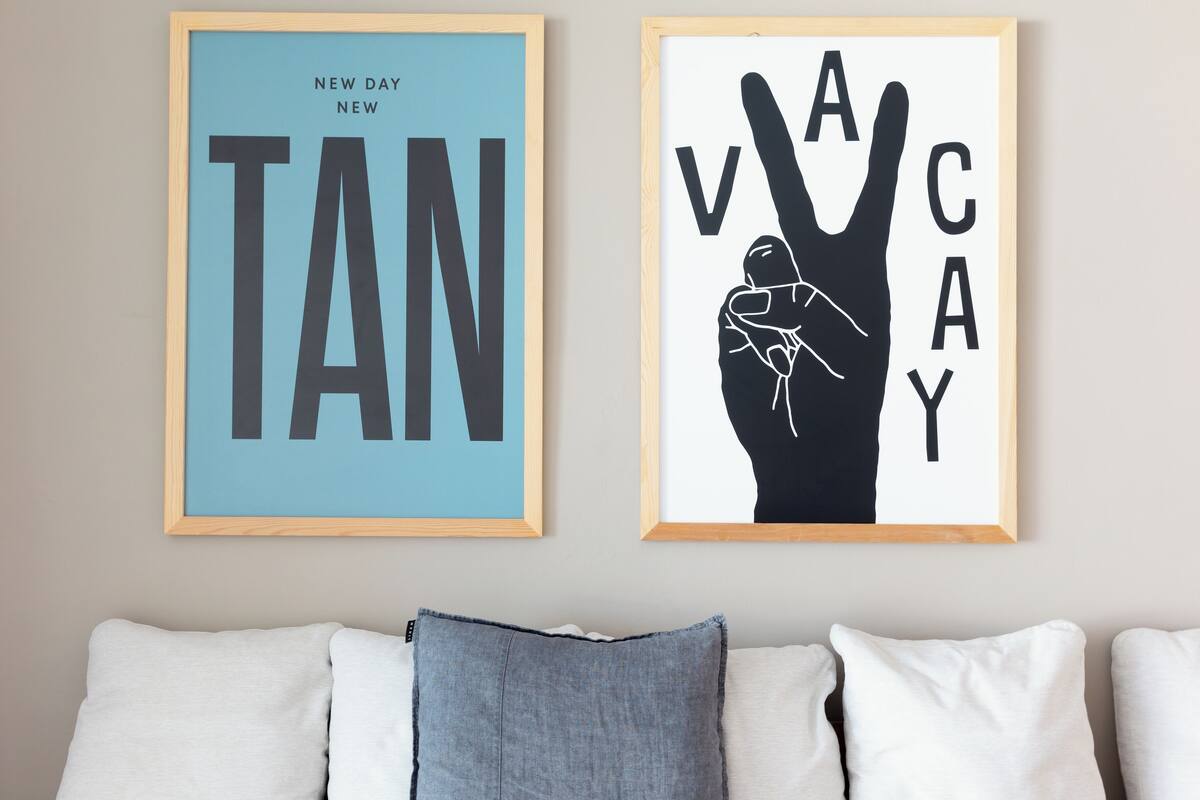 Two framed posters on a wall above a couch with pillows.
