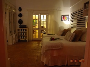 Un dormitorio con cama, mesita de noche, lámpara y puerta que da a un balcón.