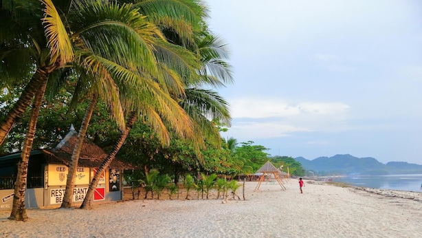 Una playa con un restaurante llamado "Old Spice Bar" y una pequeña estructura tipo cabaña.