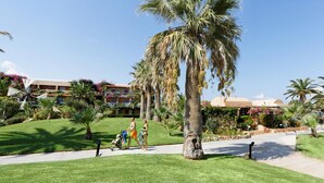 Cortile di un hotel con palme, un vialetto e un edificio con balconi.