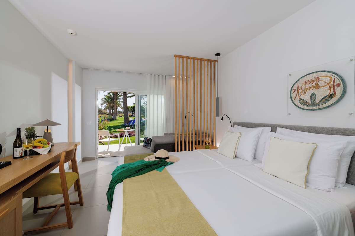 A hotel room with a bed, a desk, a chair, and a view of the outdoors.