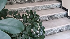 A staircase with marble steps leading to a landing with a light fixture above. - The ideal house at the foot of Acropolis. (Athina)