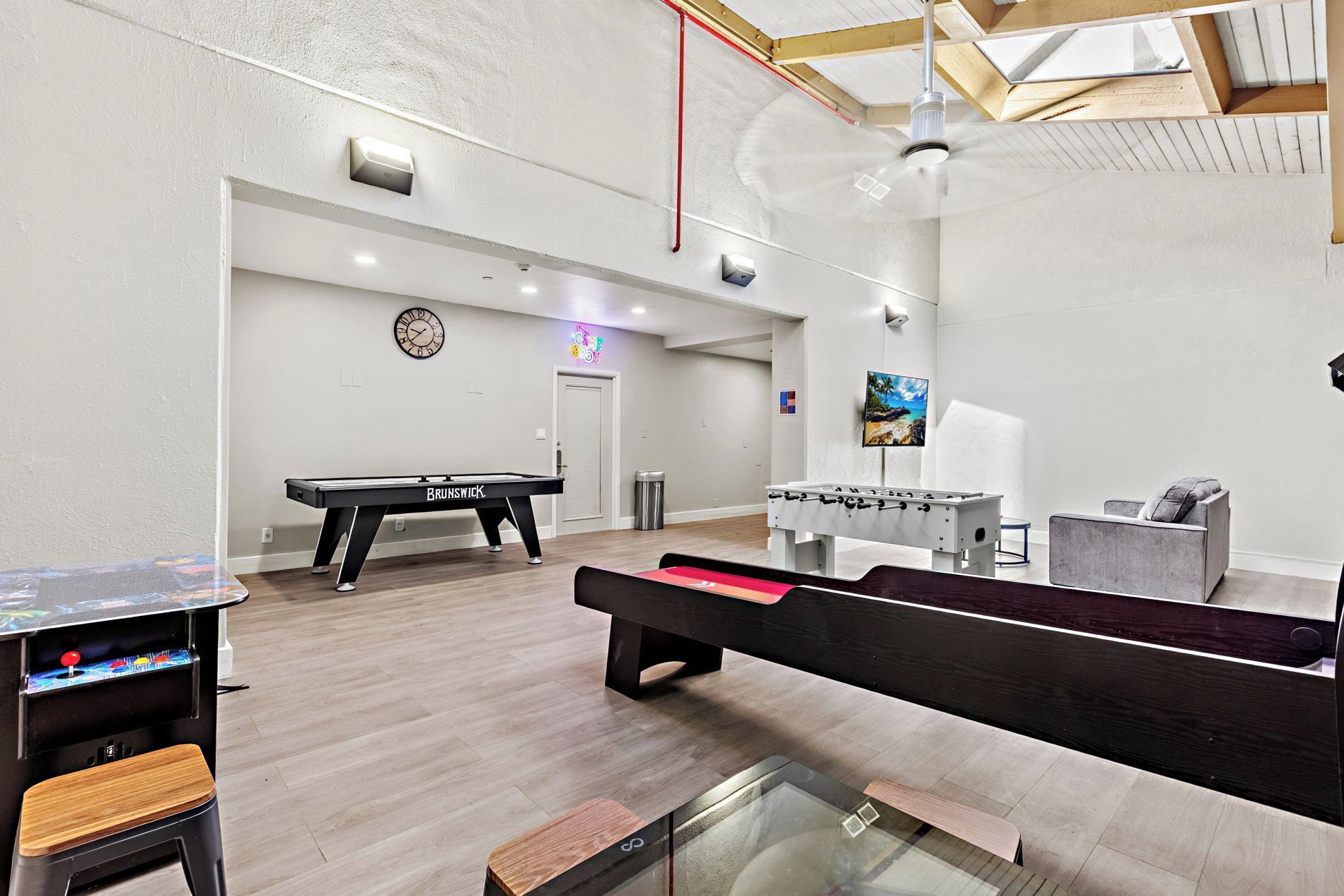 A billiards room with a pool table, foosball table, and a foosball table with a TV screen.