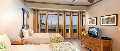 A hotel room with two beds, a television, a wooden dresser, and a view of the ocean.