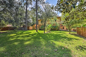 A backyard with a wooden fence, a small tree, and a building with a yellow facade.