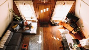 A cozy cabin interior with a sofa, a small table, a TV, and a door with curtains.