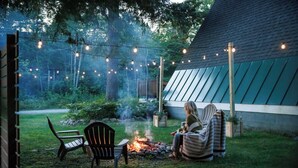 An outdoor seating area with a fire pit, chairs, and string lights.