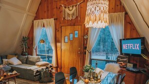 A cozy, wooden interior with a dining area, a sofa, and a TV displaying 'NETFLIX'.