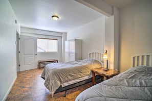 Cozy retreat with a large bed, bedside table, and bench, set against a neutral backdrop.