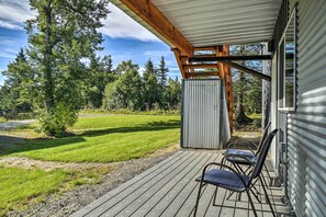 Relax on the deck with a chair and table, surrounded by a well-maintained lawn and trees.