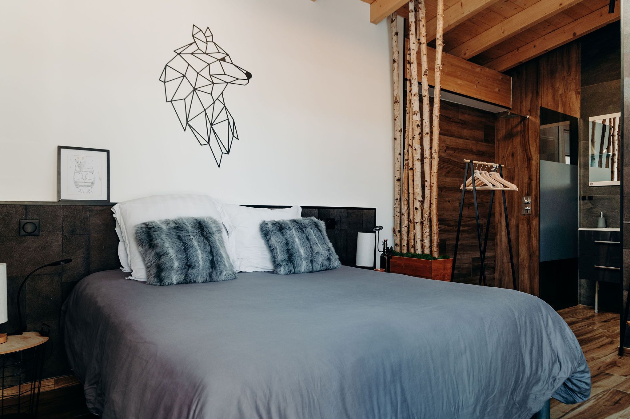 A modern bedroom with a geometric wall art, a wooden headboard, and a hanging clothes rack.