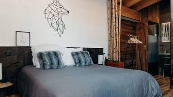 A modern bedroom with a geometric wall art, a wooden headboard, and a hanging clothes rack.