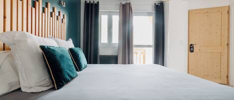 Un dormitorio con cama, cabecera de madera y vista al exterior por una ventana.