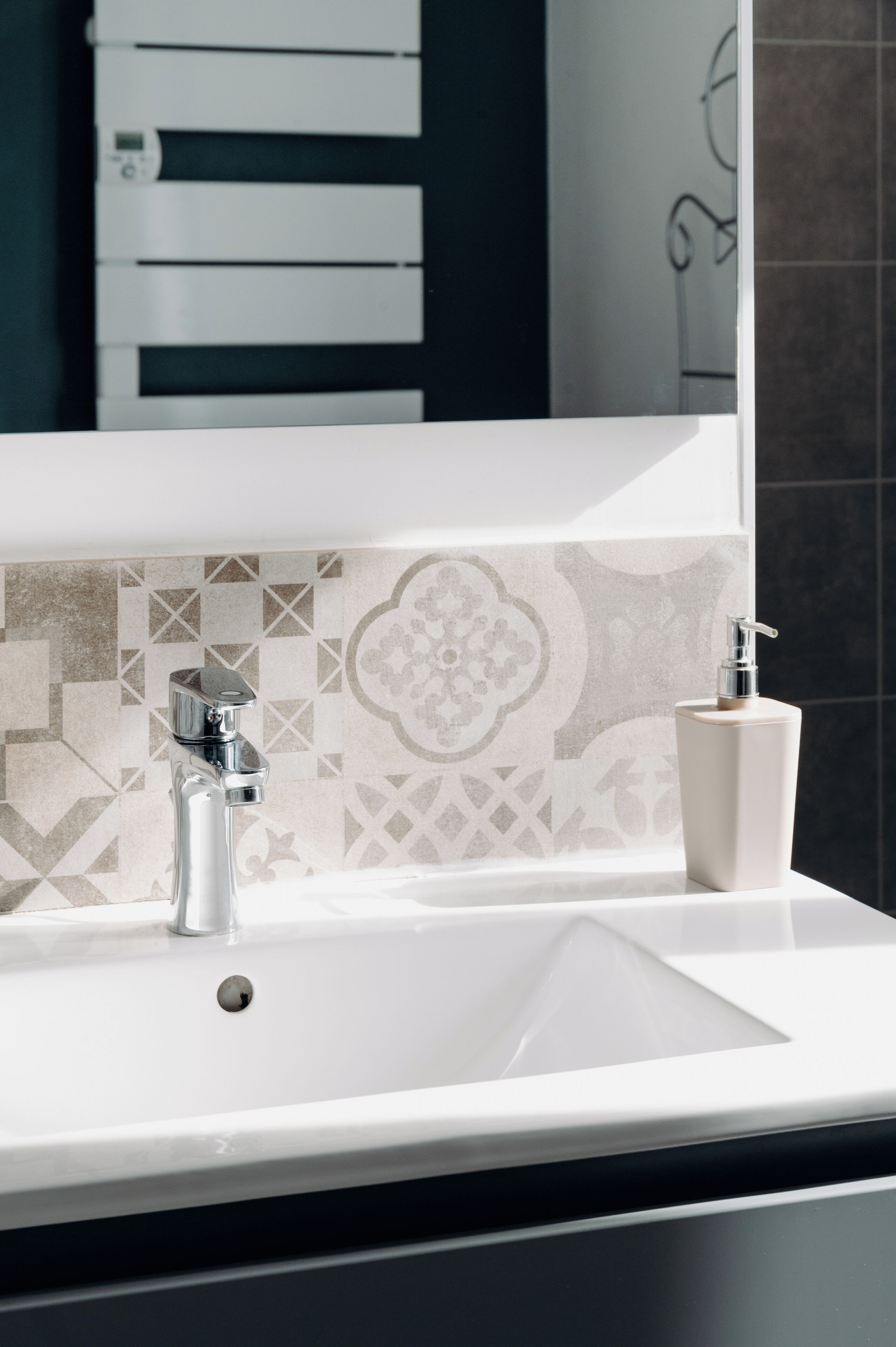 Un lavabo da bagno con un moderno rubinetto e un dispenser di sapone.