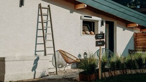 A rustic building with a wooden ladder, a wicker chair, and a sign indicating a garden and a kitchen. - La Villa d'Hélène Chambres d’hôtes et Appartements-Cluses (Cluses)
