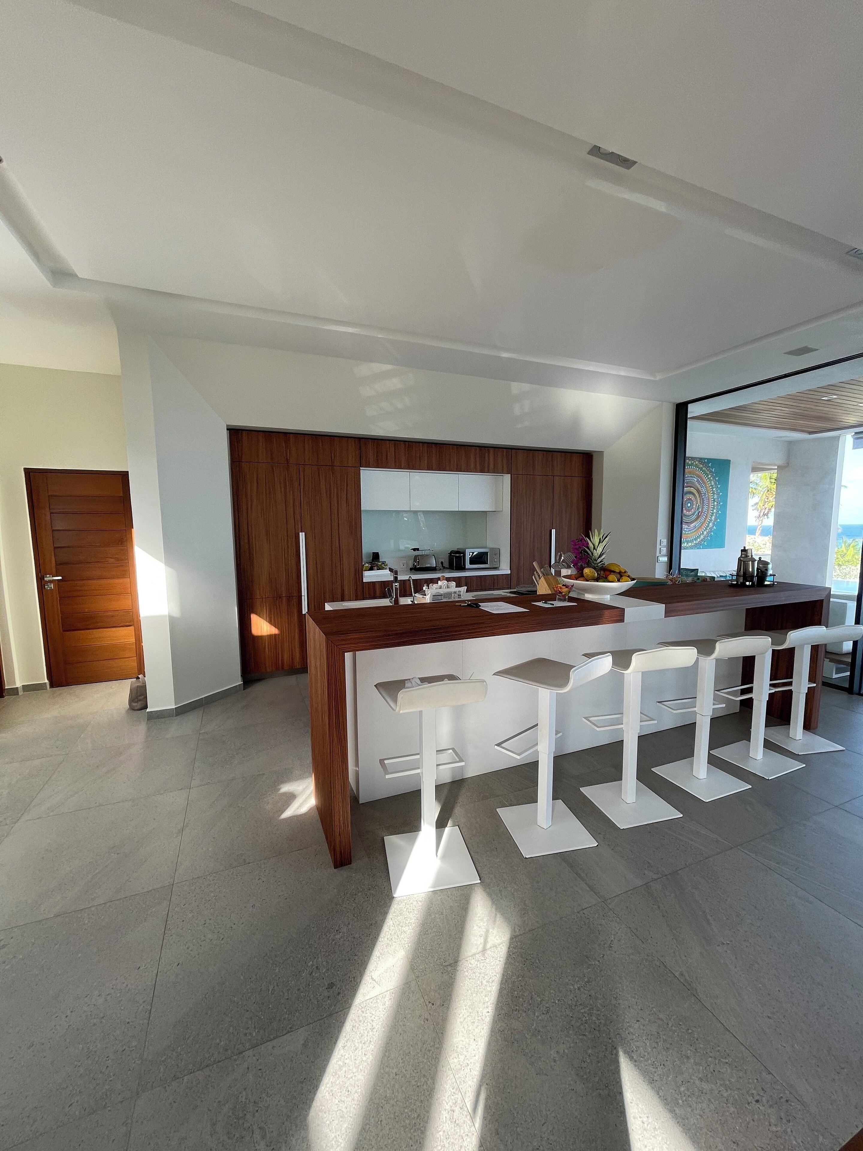A modern kitchen with a central island, bar stools, and a view of the ocean.