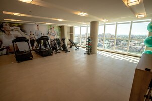 Un gimnasio con cintas de correr, bicicletas estáticas y un soporte para pesas.