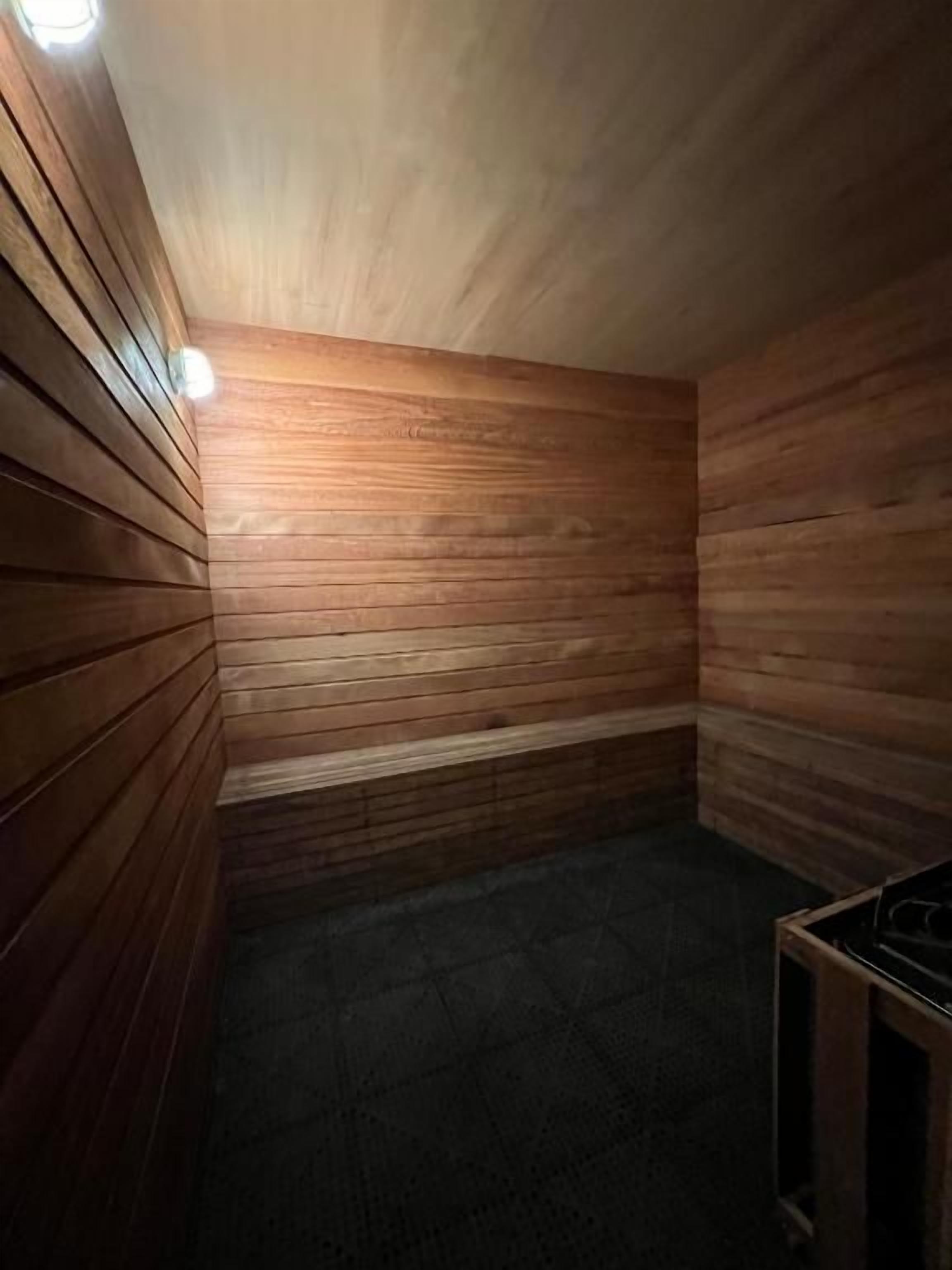 Una sala de sauna con paredes de madera y un banco.