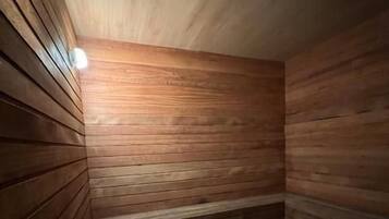 Una sala de sauna con paredes de madera y un banco.