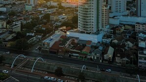 Paisagem urbana ao pôr do sol, com edifícios altos e céu claro.