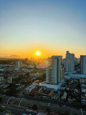 Paisagem urbana ao pôr do sol, com edifícios altos e céu claro.