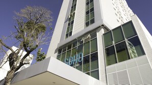 Um edifício moderno com fachada de vidro destacada e uma placa com a inscrição "COHIE".