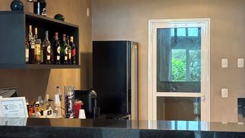 Una cocina moderna con barra, taburetes, refrigerador y ventana con vista a follaje.