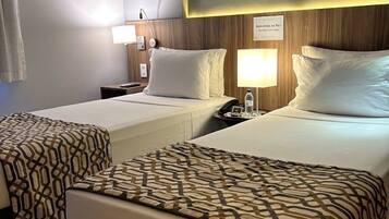 Habitación de hotel con dos camas, una mesita de noche, una lámpara y un cuadro en la pared.