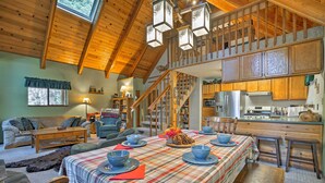 Een gezellig chaletinterieur met een eethoek, keuken en een slaaploft.