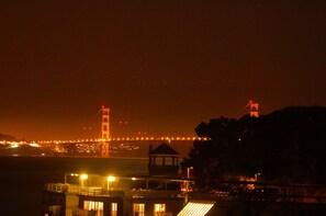 A nighttime view of a bridge with illuminated towers and a distant cityscape. - Luxury 2BR with Pool & Panoramic Golden Gate  and Skyline Views (Tiburon)