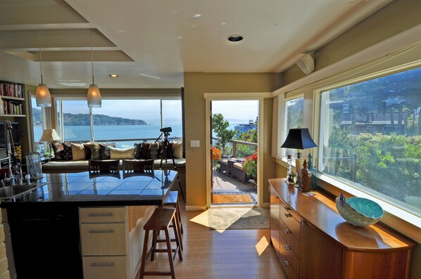 Una cocina moderna con una isla grande, un comedor con vistas y una amplia sala de estar con balcón frente al mar.