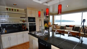 A modern kitchen with a central island, built-in appliances, and a view of the sea.