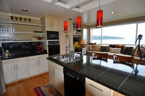 Una cocina moderna con una isla central, electrodomésticos integrados y vistas al mar.