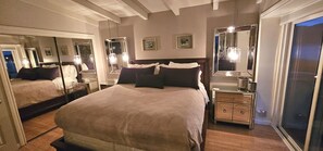 A well-lit bedroom with a large bed, bedside tables, a dresser, and multiple mirrors. - Luxury 2BR with Pool & Panoramic Golden Gate  and Skyline Views (Tiburon)