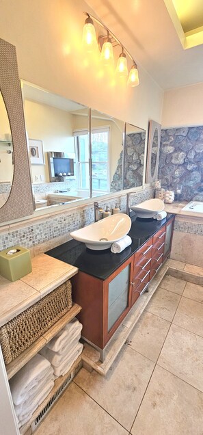 A modern bathroom with two sinks, a large mirror, and a stone accent wall. - Luxury 2BR with Pool & Panoramic Golden Gate  and Skyline Views (Tiburon)