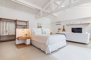 A modern bedroom with a large bed, bedside tables, a wardrobe, a television, and artwork on the walls. - Hotel Aretê (Búzios)