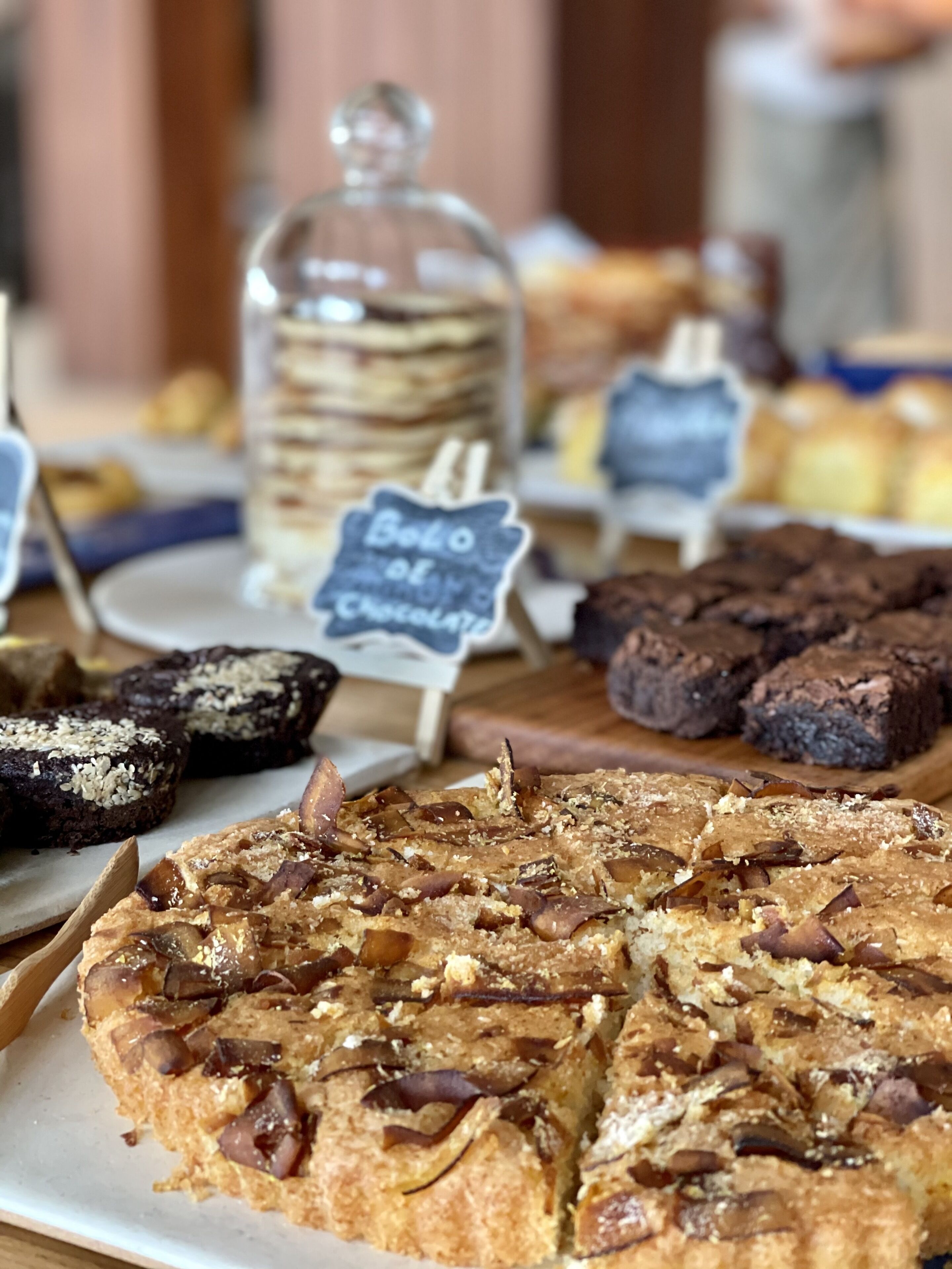 A variety of baked goods including a chocolate cake topped with nuts and a sign indicating it is a chocolate cake.