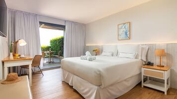 Habitación de hotel con una cama grande, un escritorio con lámpara, una silla y una mesita.