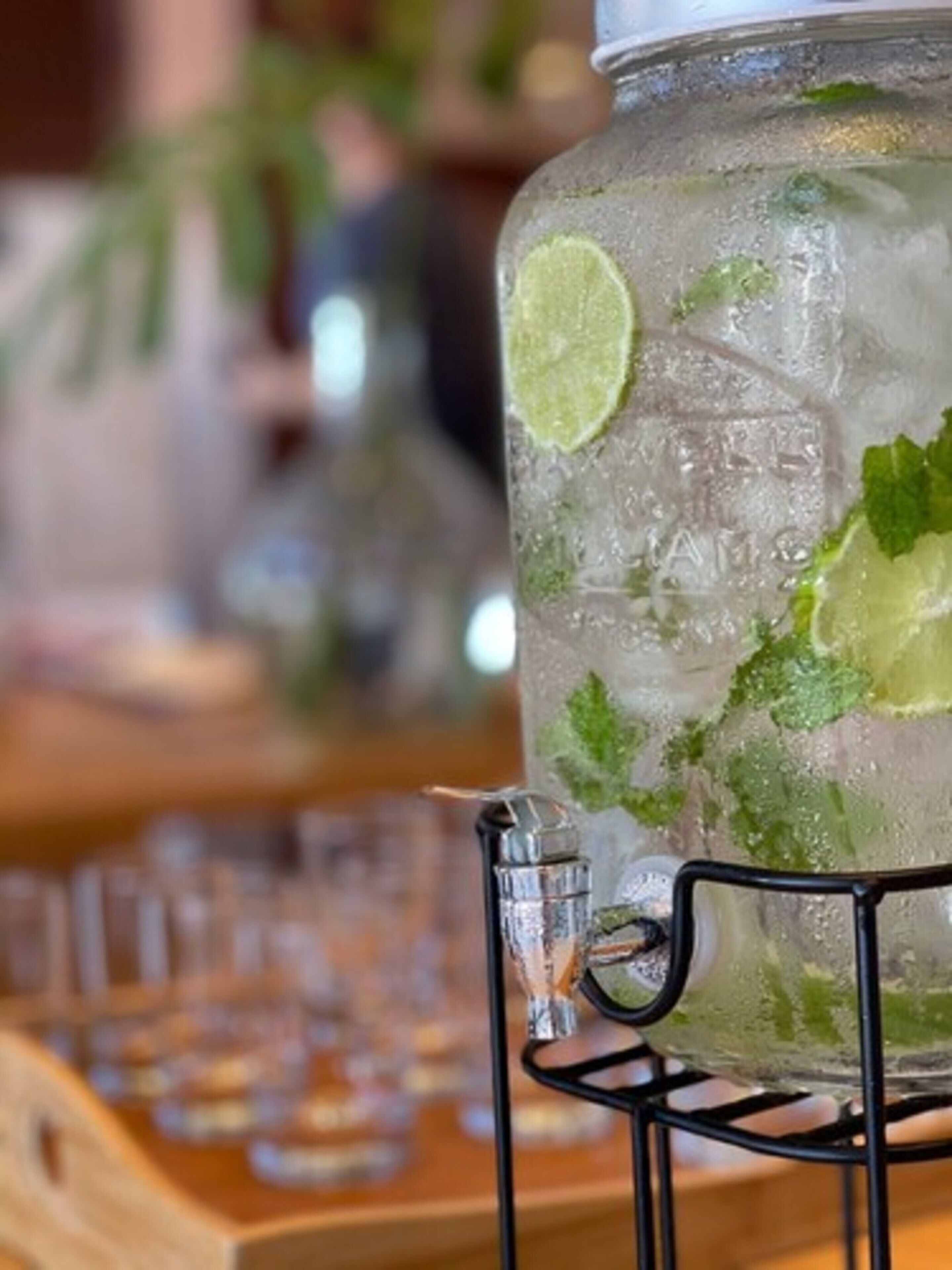 A glass jar filled with ice and lime slices, placed on a metal stand.