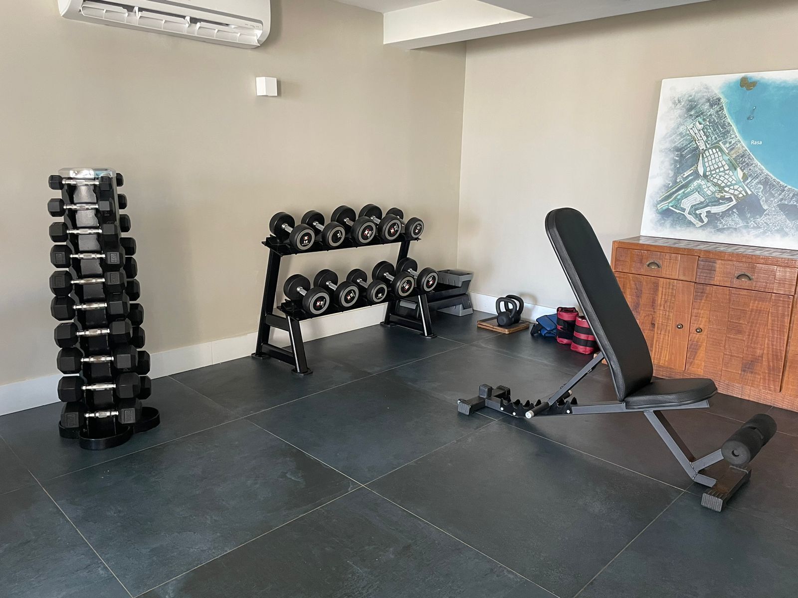 A home gym with a dumbbell rack, a bench, and a weight plate rack.