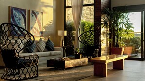 A modern living room with a sofa, a wooden coffee table, a black chair, and a potted plant. - Hotel Aretê (Búzios)
