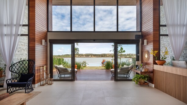 A spacious indoor area with a large window overlooking a body of water and a distant landscape. - Hotel Aretê (Búzios)