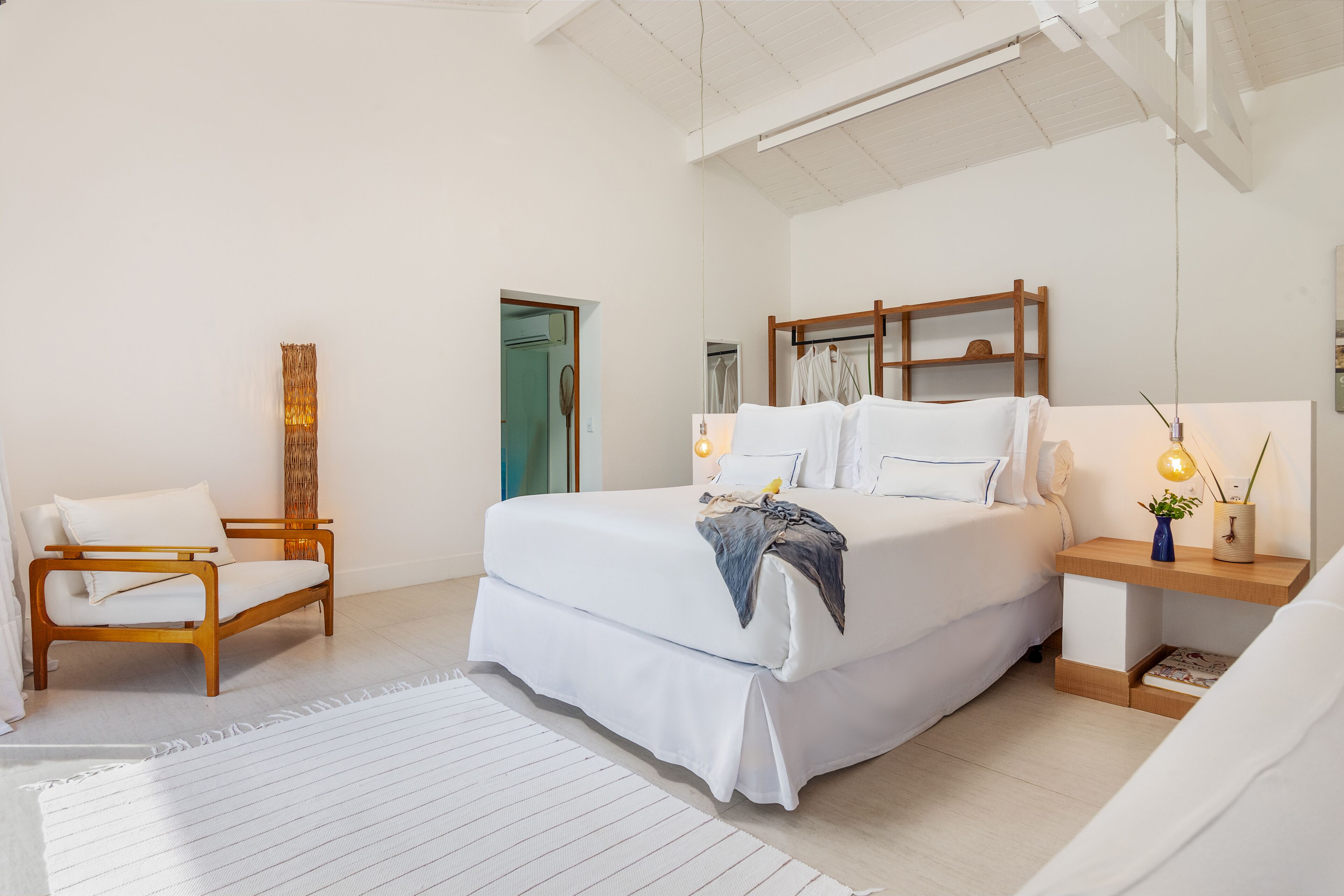 A modern bedroom with a large bed, bedside tables, a chair, and a wardrobe.