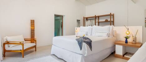 A modern bedroom with a large bed, bedside tables, a chair, and a wardrobe.