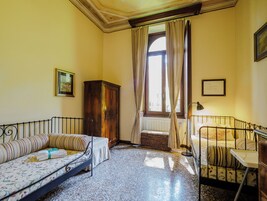 A room with a bed, a sofa, a cabinet, and a window with curtains.