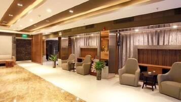 A spacious lobby with a marble floor, multiple seating areas, and a reception desk.