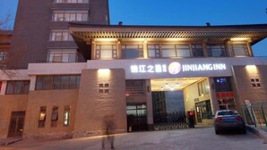 L’entrée d’un hôtel, avec une enseigne indiquant « JINJIANGINN », et un bâtiment moderne sur lequel est apposée une autre enseigne.