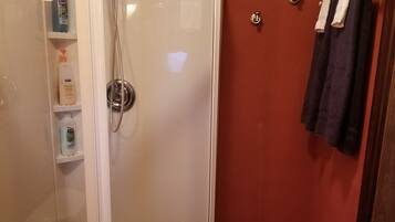 A bathroom with a glass shower enclosure, a toilet, and a towel rack.