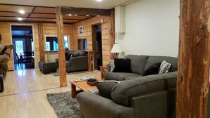 A modern living room with a sofa, coffee table, and wooden beams. - Northern Sky Lodge (Fairbanks)