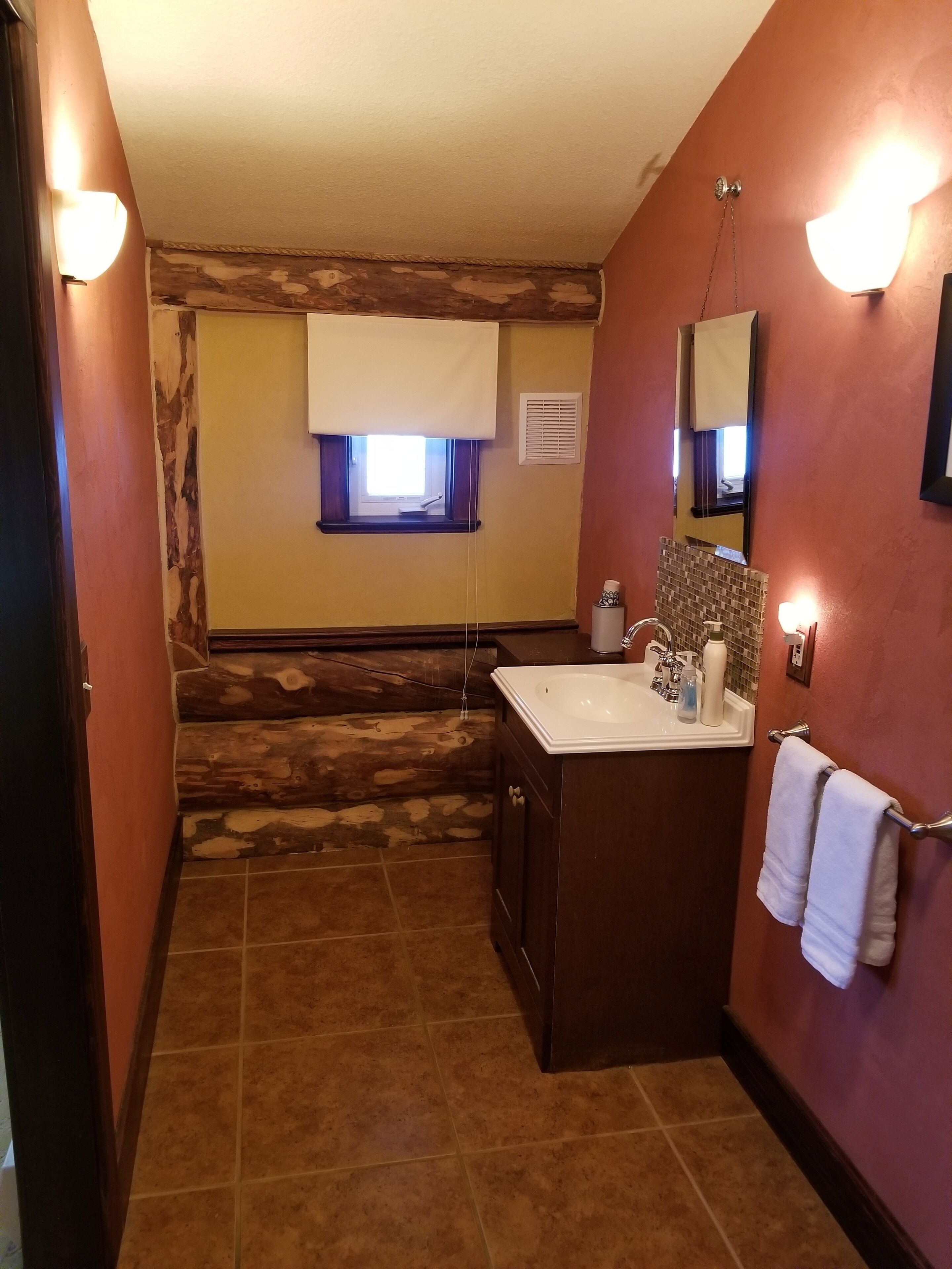 Un baño con una pared de acento de piedra, un lavamanos con espejo y un perchero para toallas.